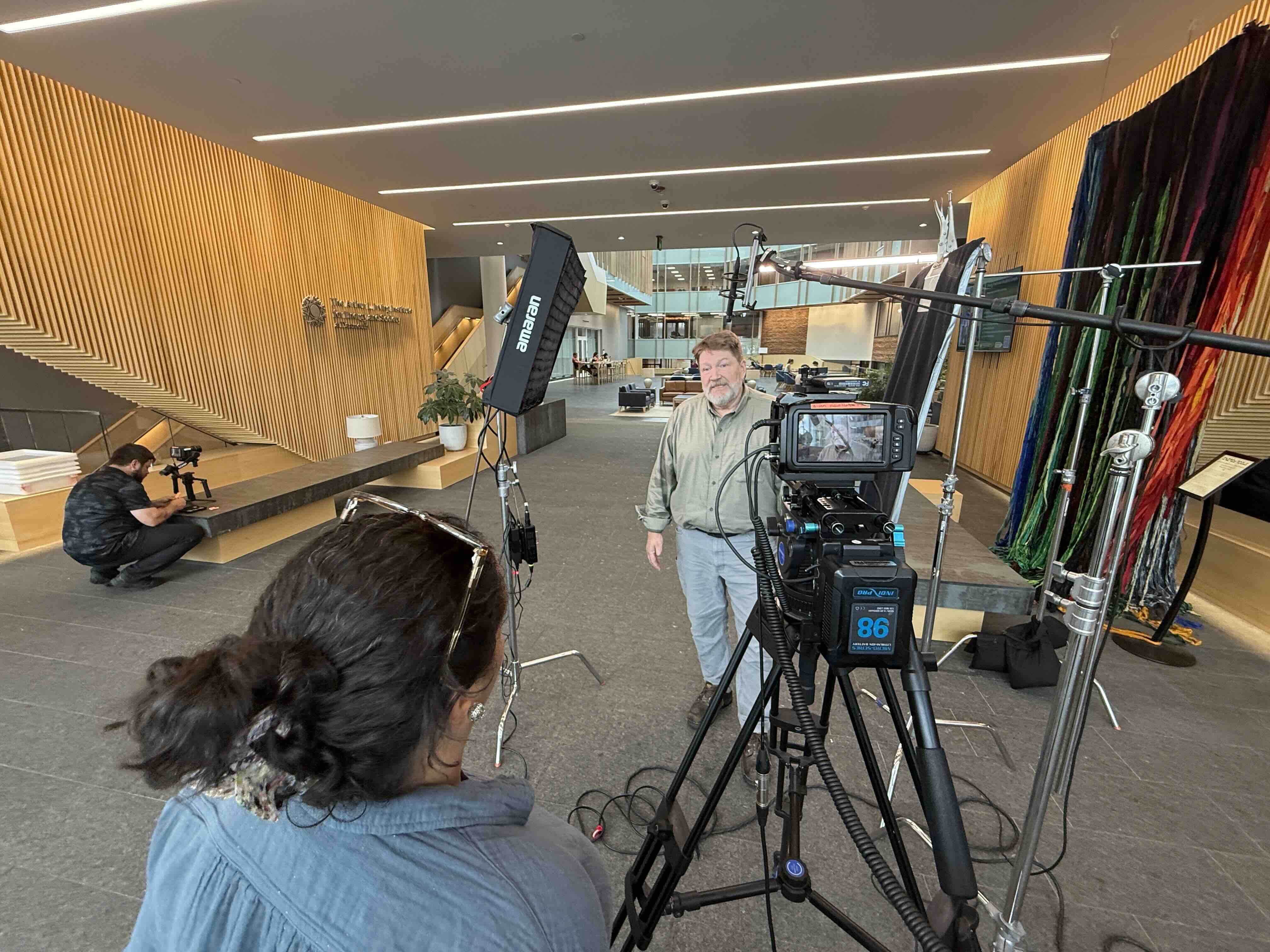 Standing interview setup in a wood-paneled lobby, with softbox lighting, a boom microphone, and two RetroMotion crew members